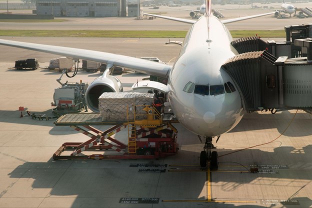 Cargo plane being loaded with goods using a cargo loader at an airport.