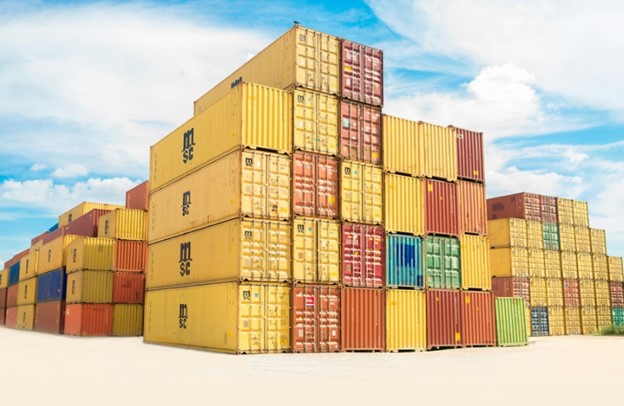 Large red and yellow containers are stacked on top of each other. Above, there is a blue sky with white clouds.