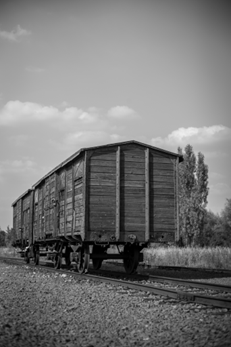 Ett svartvitt fotografi på en gammal träcontainer på en järnväg.