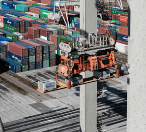 En hamn fylld med containrar i olika färger. I förgrunden syns en orange container lyft.