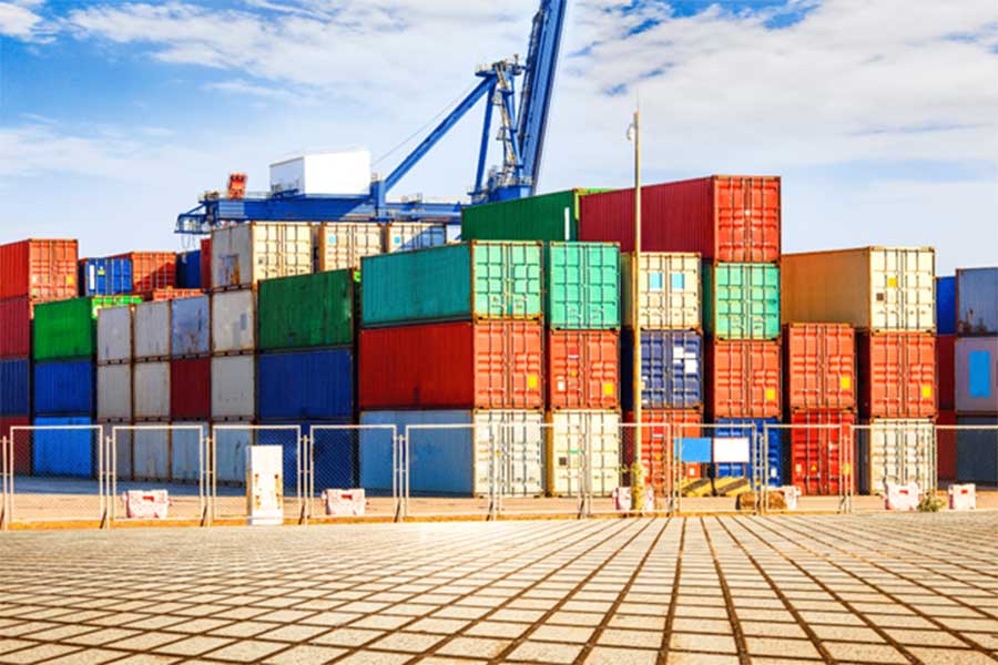 Containers in various sizes and colors stacked on top of each other in a port.